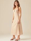 Este vestido tiene un diseño elegante y minimalista. De largo midi y tirantes delgados, destaca por su escote corazón con un pequeño corte central que aporta un toque moderno y sutilmente sensual. La tela estructurada y ligera lo hace ideal para climas cálidos, y combinado con sandalias de tacón y joyería dorada, logra un look sofisticado y femenino. 