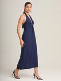 El vestido navy midi combina una tela fluida con un escote halter profundo, creando una prenda moderna y versátil. Ideal para eventos formales o salidas nocturnas