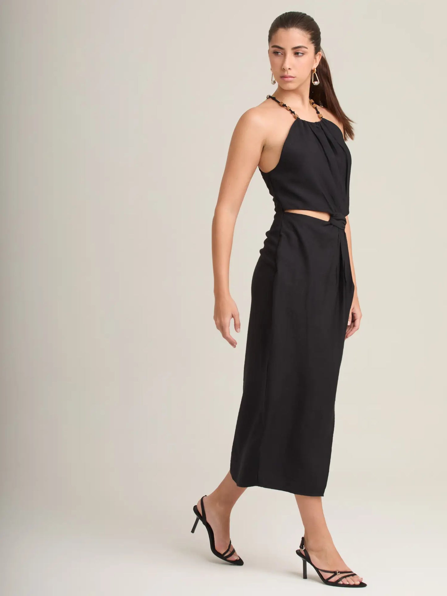 El vestido negro Seoul incluye un nudo frontal que define la cintura y aporta volumen sutil. Su corte midi y abertura en la pierna crean un look femenino, moderno y elegante.