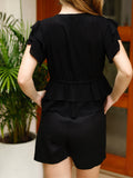 Blusa de escote en V profundo con detalle de amarre frontal. Presenta volantes en las mangas y doble capa de volantes en la parte inferior, lo que le aporta un toque femenino y romántico. El ajuste en la cintura crea una silueta favorecedora y delicada.

Detalles:

Color: Negro

Material: 100% poliéster

Cuidado: Lavar a mano con jabón suave, por separado.No dejar en remojo. Planchar a temperatura alta.
