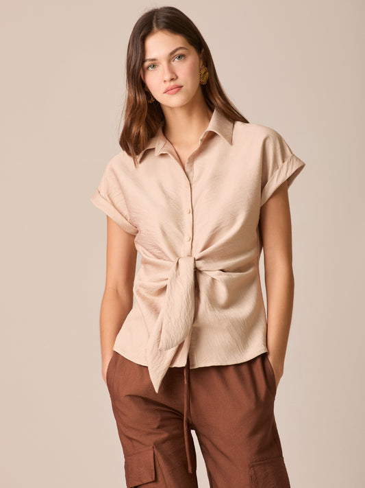 Blusa camisera de manga corta con cuello clásico y tapeta de botones. Destaca el nudo frontal que define la cintura, con puños vueltos y dobladillo curvo con pequeñas aberturas laterales. Caída ligera y fit relajado que estiliza y funciona del día a la noche

Detalles:

Color: Sand

Material: 87% Rayón 13% Poliamida.