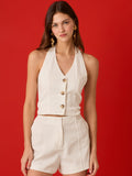 Blusa tipo chaleco con cuello halter y escote en V. Silueta entallada con cortes que definen el torso, cierre frontal con tres botones protagonistas y largo a la cintura. Un top sastre, pulcro y femenino que eleva cualquier look.

Detalles:

Color: Blanco

Material: 70% Rayón 30% Lino