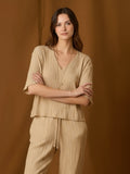 Blusa de silueta relajada con escote en V y mangas a medio brazo. Su textura sutilmente arrugada y caída fluida aportan movimiento y un toque moderno. Largo a la cadera con bajo recto para un fit favorecedor y cómodo. Versátil para el día o la noche