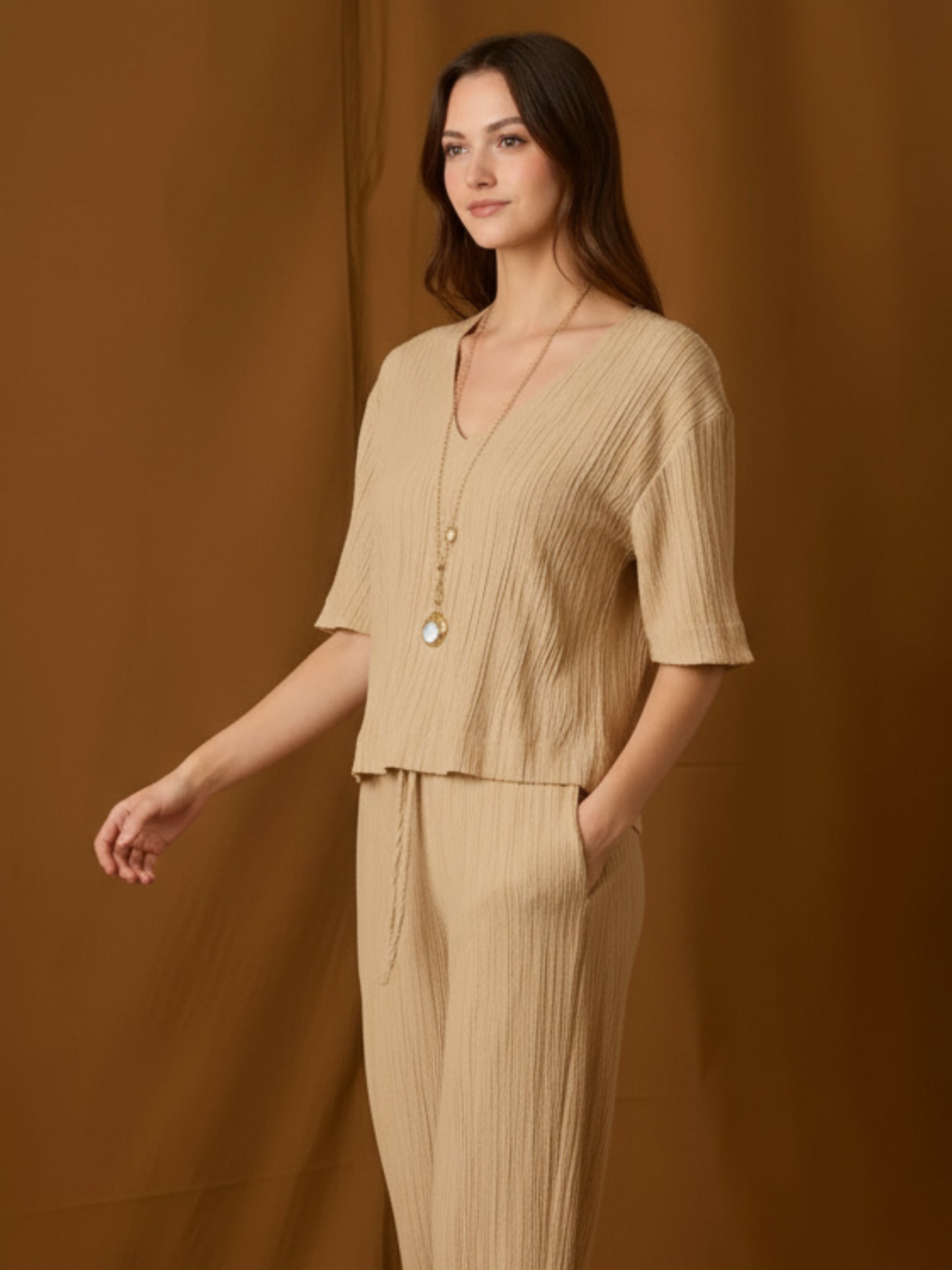 Blusa de silueta relajada con escote en V y mangas a medio brazo. Su textura sutilmente arrugada y caída fluida aportan movimiento y un toque moderno. Largo a la cadera con bajo recto para un fit favorecedor y cómodo. Versátil para el día o la noche