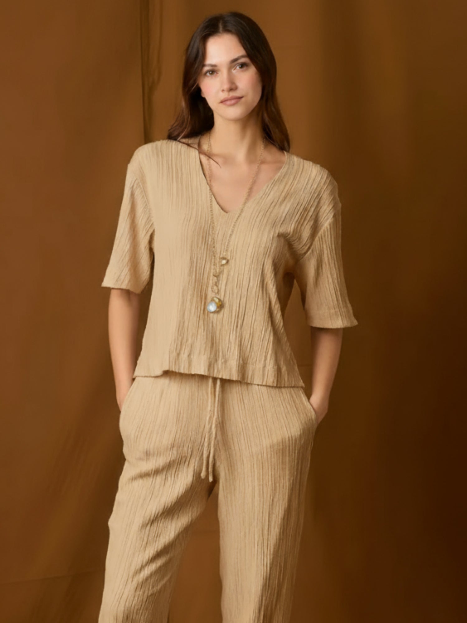 Blusa de silueta relajada con escote en V y mangas a medio brazo. Su textura sutilmente arrugada y caída fluida aportan movimiento y un toque moderno. Largo a la cadera con bajo recto para un fit favorecedor y cómodo. Versátil para el día o la noche