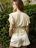 Blusa de escote en V profundo con detalle de amarre frontal. Presenta volantes en las mangas y doble capa de volantes en la parte inferior, lo que le aporta un toque femenino y romántico. El ajuste en la cintura crea una silueta favorecedora y delicada.

Detalles:

Color: Vainilla

Material: 100% poliéster