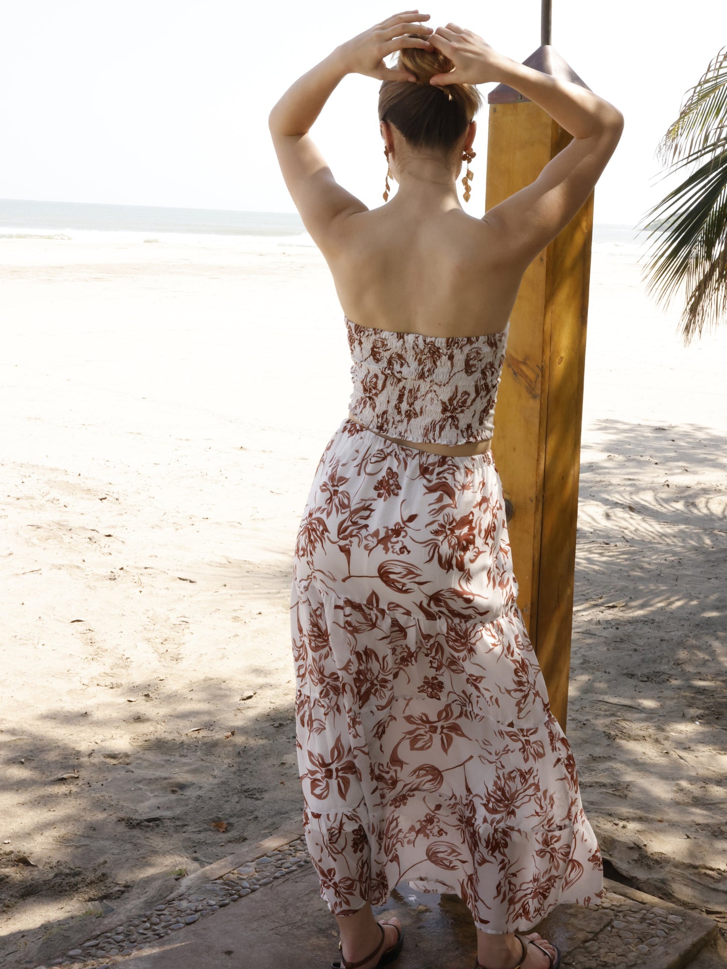 Esta falda es de corte largo, tipo maxi, confeccionada en una tela ligera ideal para climas cálidos. Presenta un estampado floral en tonos marrones sobre fondo blanco, lo que le da un estilo fresco y veraniego. Tiene un diseño de cintura alta con pretina plana que estiliza la figura y caída fluida con ligero vuelo, aportando movimiento al caminar. Es una prenda cómoda y elegante, perfecta para looks de playa o escapadas tropicales.

Detalles:

Color: Blanco

Material: 100% Lyocel