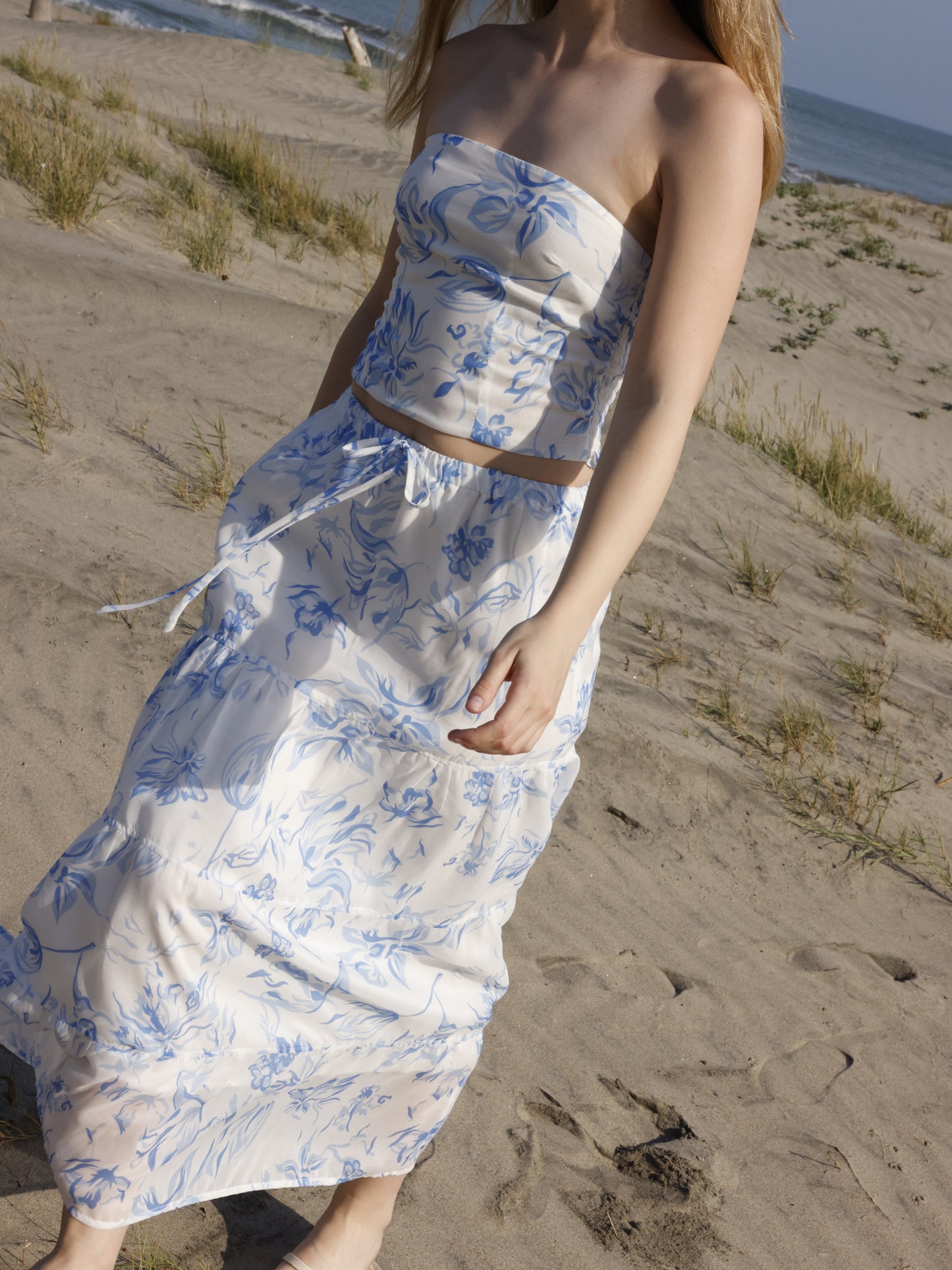 Esta falda es de corte largo, tipo maxi, confeccionada en una tela ligera ideal para climas cálidos. Presenta un estampado floral en tonos marrones sobre fondo blanco, lo que le da un estilo fresco y veraniego. Tiene un diseño de cintura alta con pretina plana que estiliza la figura y caída fluida con ligero vuelo, aportando movimiento al caminar. Es una prenda cómoda y elegante, perfecta para looks de playa o escapadas tropicales.

Detalles:

Color: Blanco

Material: 100% Lyocel