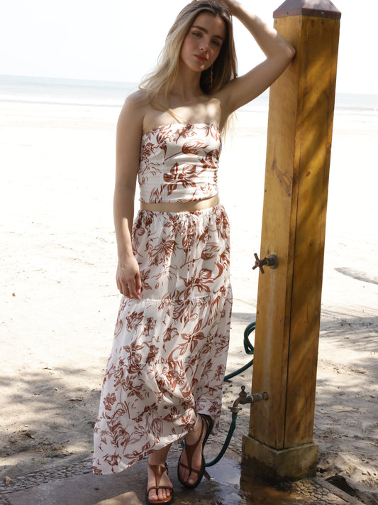 Esta falda es de corte largo, tipo maxi, confeccionada en una tela ligera ideal para climas cálidos. Presenta un estampado floral en tonos marrones sobre fondo blanco, lo que le da un estilo fresco y veraniego. Tiene un diseño de cintura alta con pretina plana que estiliza la figura y caída fluida con ligero vuelo, aportando movimiento al caminar. Es una prenda cómoda y elegante, perfecta para looks de playa o escapadas tropicales.

Detalles:

Color: Blanco

Material: 100% Lyocel