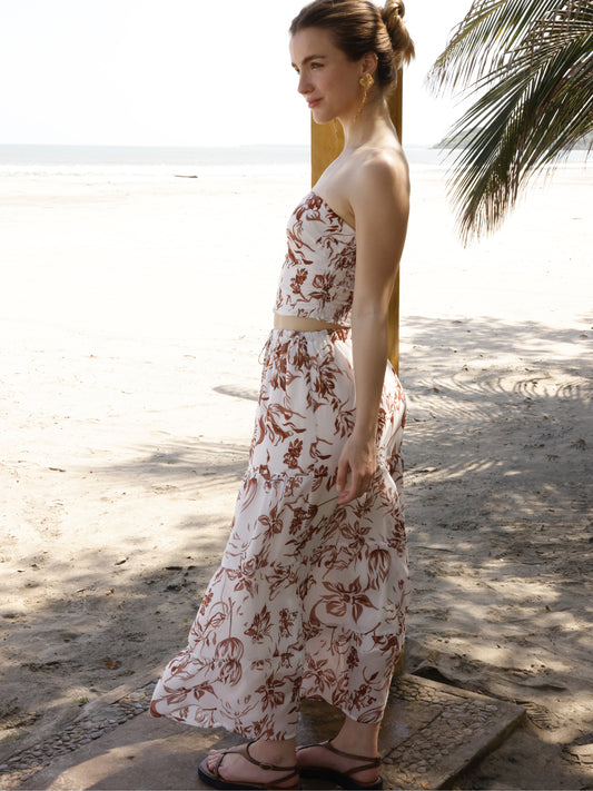 Esta falda es de corte largo, tipo maxi, confeccionada en una tela ligera ideal para climas cálidos. Presenta un estampado floral en tonos marrones sobre fondo blanco, lo que le da un estilo fresco y veraniego. Tiene un diseño de cintura alta con pretina plana que estiliza la figura y caída fluida con ligero vuelo, aportando movimiento al caminar. Es una prenda cómoda y elegante, perfecta para looks de playa o escapadas tropicales.

Detalles:

Color: Blanco

Material: 100% Lyocel