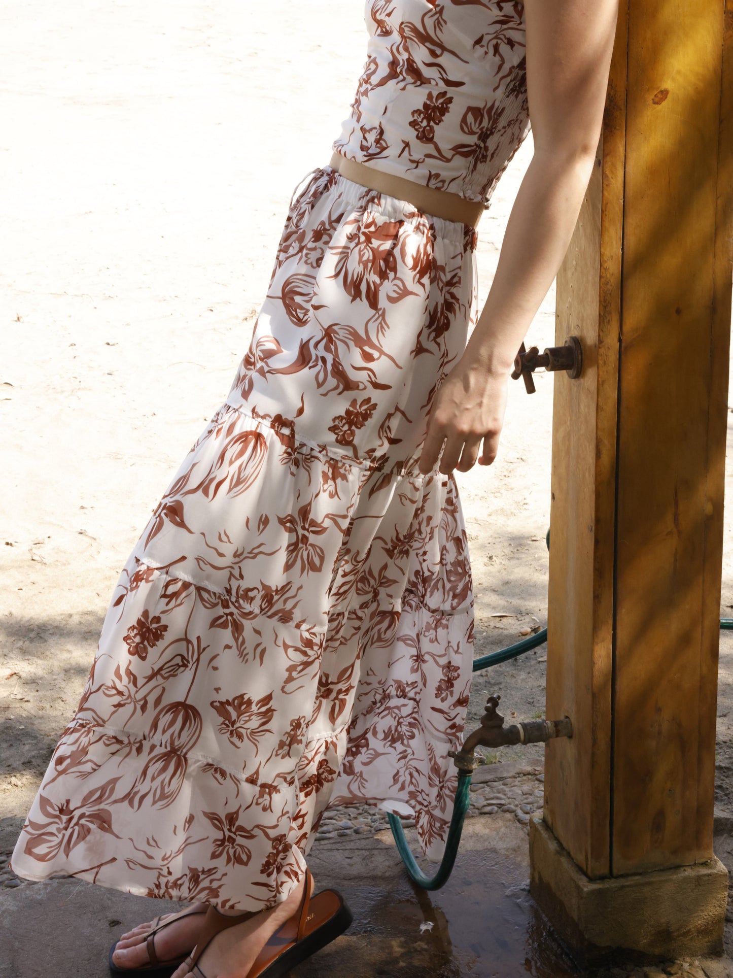Esta falda es de corte largo, tipo maxi, confeccionada en una tela ligera ideal para climas cálidos. Presenta un estampado floral en tonos marrones sobre fondo blanco, lo que le da un estilo fresco y veraniego. Tiene un diseño de cintura alta con pretina plana que estiliza la figura y caída fluida con ligero vuelo, aportando movimiento al caminar. Es una prenda cómoda y elegante, perfecta para looks de playa o escapadas tropicales.

Detalles:

Color: Blanco

Material: 100% Lyocel