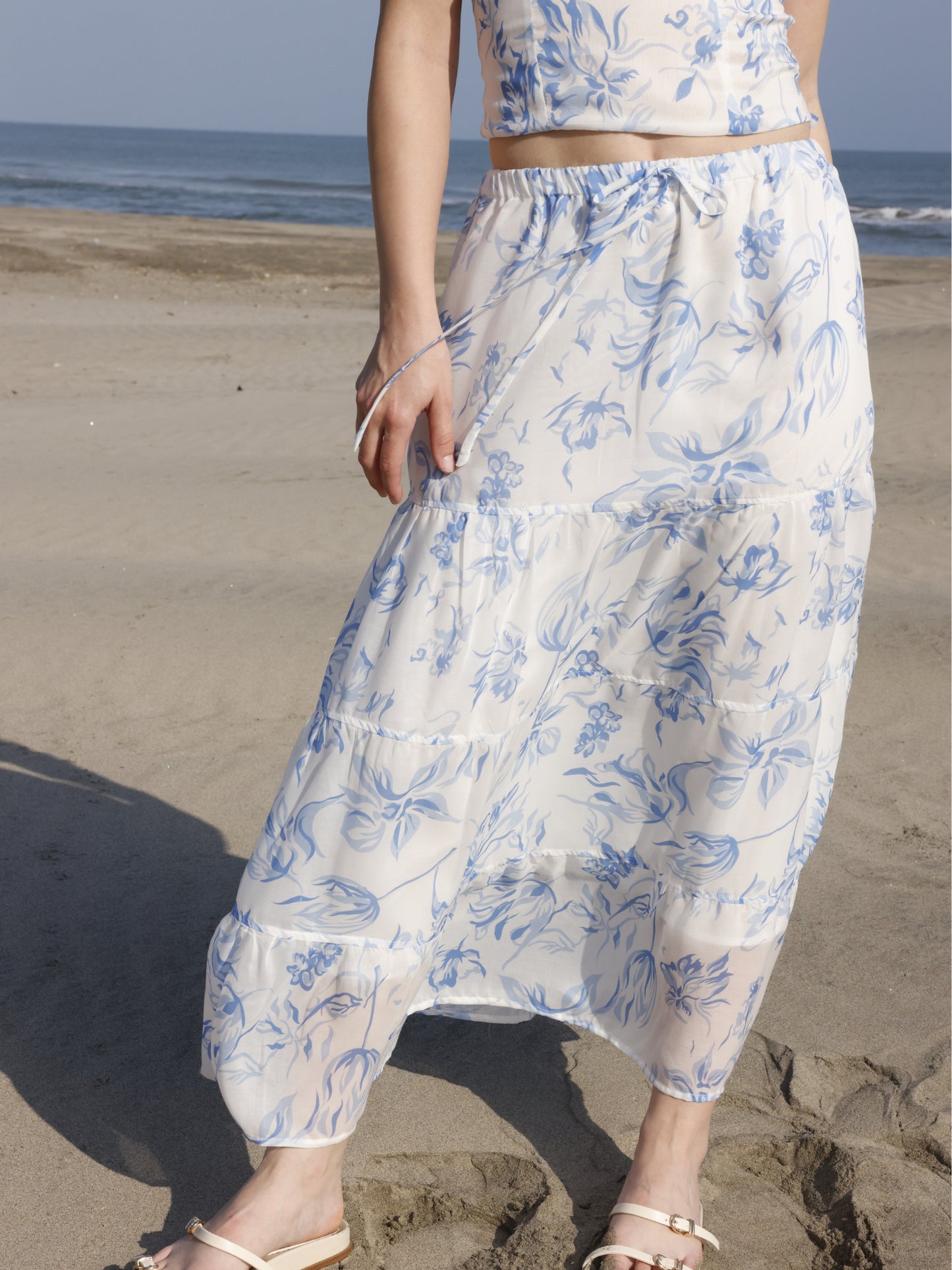 Esta falda es de corte largo, tipo maxi, confeccionada en una tela ligera ideal para climas cálidos. Presenta un estampado floral en tonos marrones sobre fondo blanco, lo que le da un estilo fresco y veraniego. Tiene un diseño de cintura alta con pretina plana que estiliza la figura y caída fluida con ligero vuelo, aportando movimiento al caminar. Es una prenda cómoda y elegante, perfecta para looks de playa o escapadas tropicales.

Detalles:

Color: Blanco

Material: 100% Lyocel