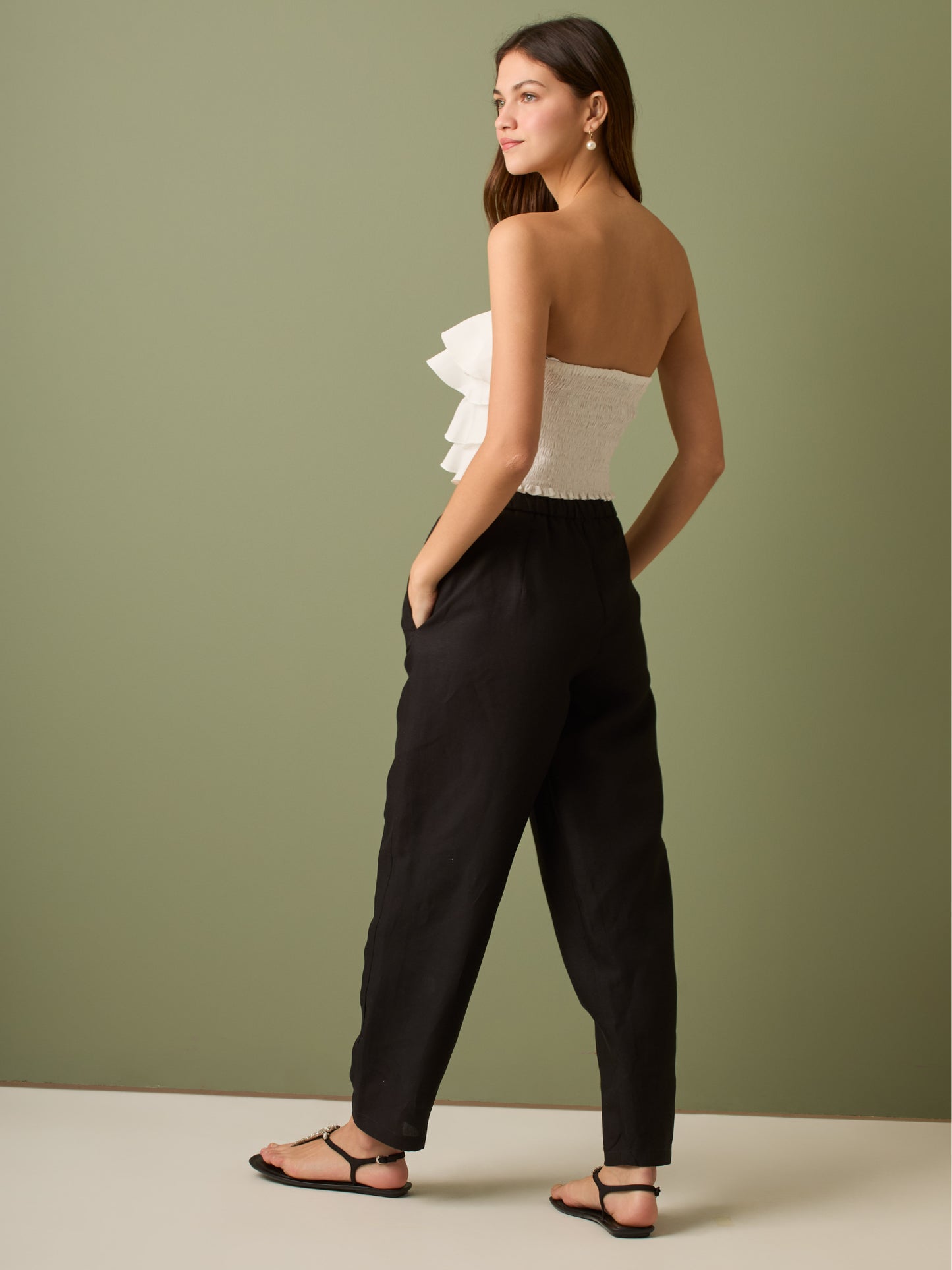 Pantalón de tiro medio con cintura elástica y cordón ajustable. Silueta relajada que cae con volumen en la cadera y se afina al tobillo, con bolsillos laterales y cortes decorativos en la pierna. Largo al tobillo con pequeña abertura en el bajo: la base moderna y versátil para elevar looks de día o de noche.

Detalles:

Color: Negro