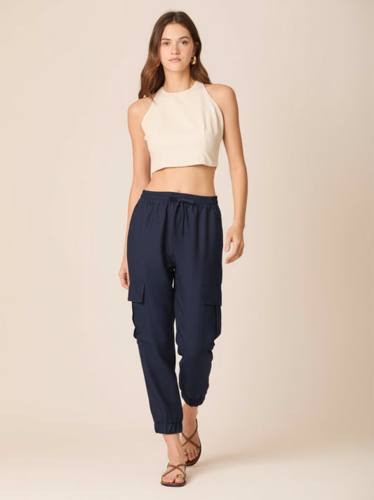 Este pantalón combina comodidad y estilo en un diseño moderno. Presenta pretina elástica con cordón ajustable que se adapta perfectamente a la cintura, bolsillos laterales tipo cargo que aportan un aire práctico y urbano, y terminaciones con elástico en los tobillos que estilizan la silueta. Su corte relajado lo convierte en una prenda versátil y actual, ideal para un look casual y sofisticado al mismo tiempo. Perfecto para quienes buscan frescura y dinamismo sin perder elegancia.