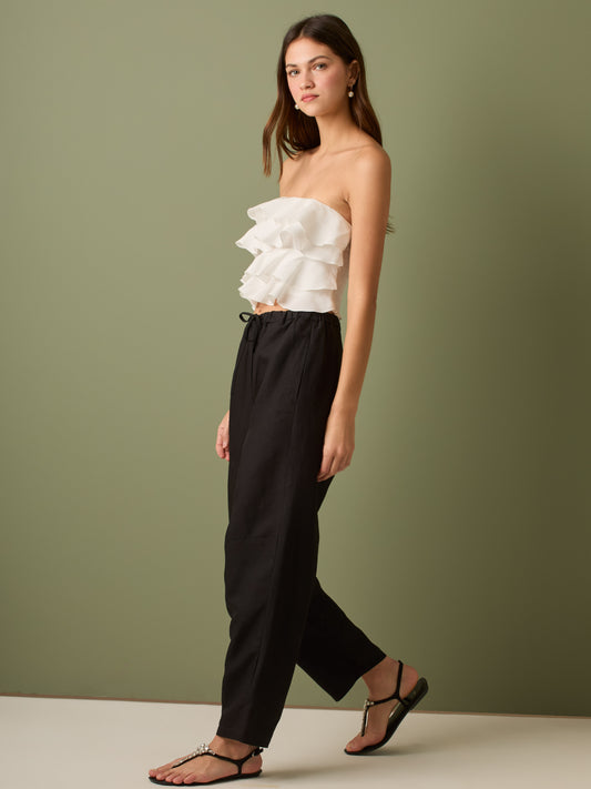 Pantalón de tiro medio con cintura elástica y cordón ajustable. Silueta relajada que cae con volumen en la cadera y se afina al tobillo, con bolsillos laterales y cortes decorativos en la pierna. Largo al tobillo con pequeña abertura en el bajo: la base moderna y versátil para elevar looks de día o de noche.

Detalles:

Color: Negro