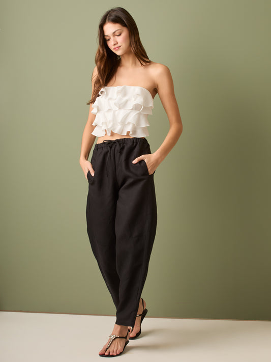 Pantalón de tiro medio con cintura elástica y cordón ajustable. Silueta relajada que cae con volumen en la cadera y se afina al tobillo, con bolsillos laterales y cortes decorativos en la pierna. Largo al tobillo con pequeña abertura en el bajo: la base moderna y versátil para elevar looks de día o de noche.

Detalles:

Color: Negro