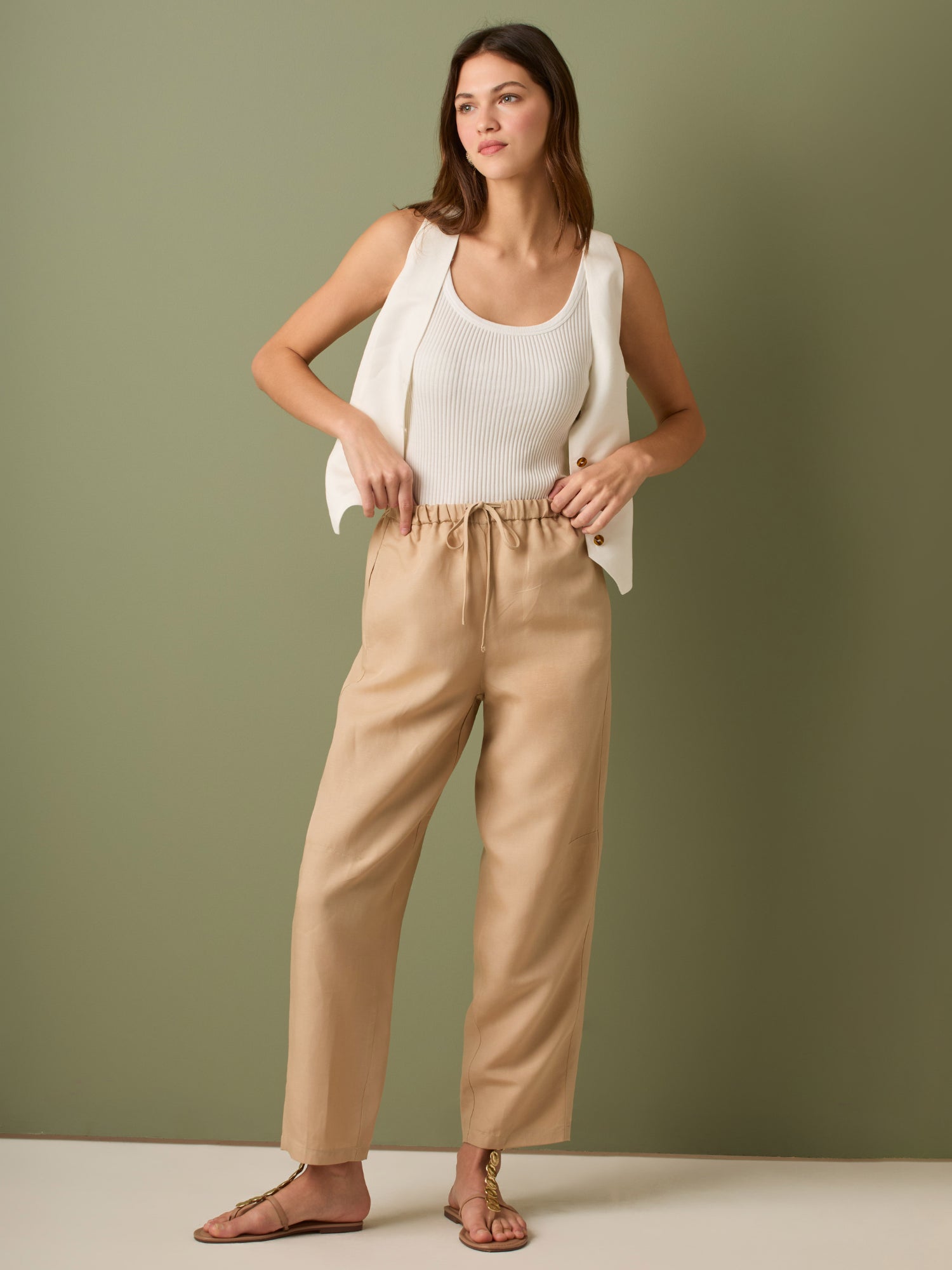 Pantalón de tiro medio con cintura elástica y cordón ajustable. Silueta relajada que cae con volumen en la cadera y se afina al tobillo, con bolsillos laterales y cortes decorativos en la pierna. Largo al tobillo con pequeña abertura en el bajo: la base moderna y versátil para elevar looks de día o de noche.

Detalles:

Color: Sand

Material: 77% Tencel 23% Lino 100% Rayón