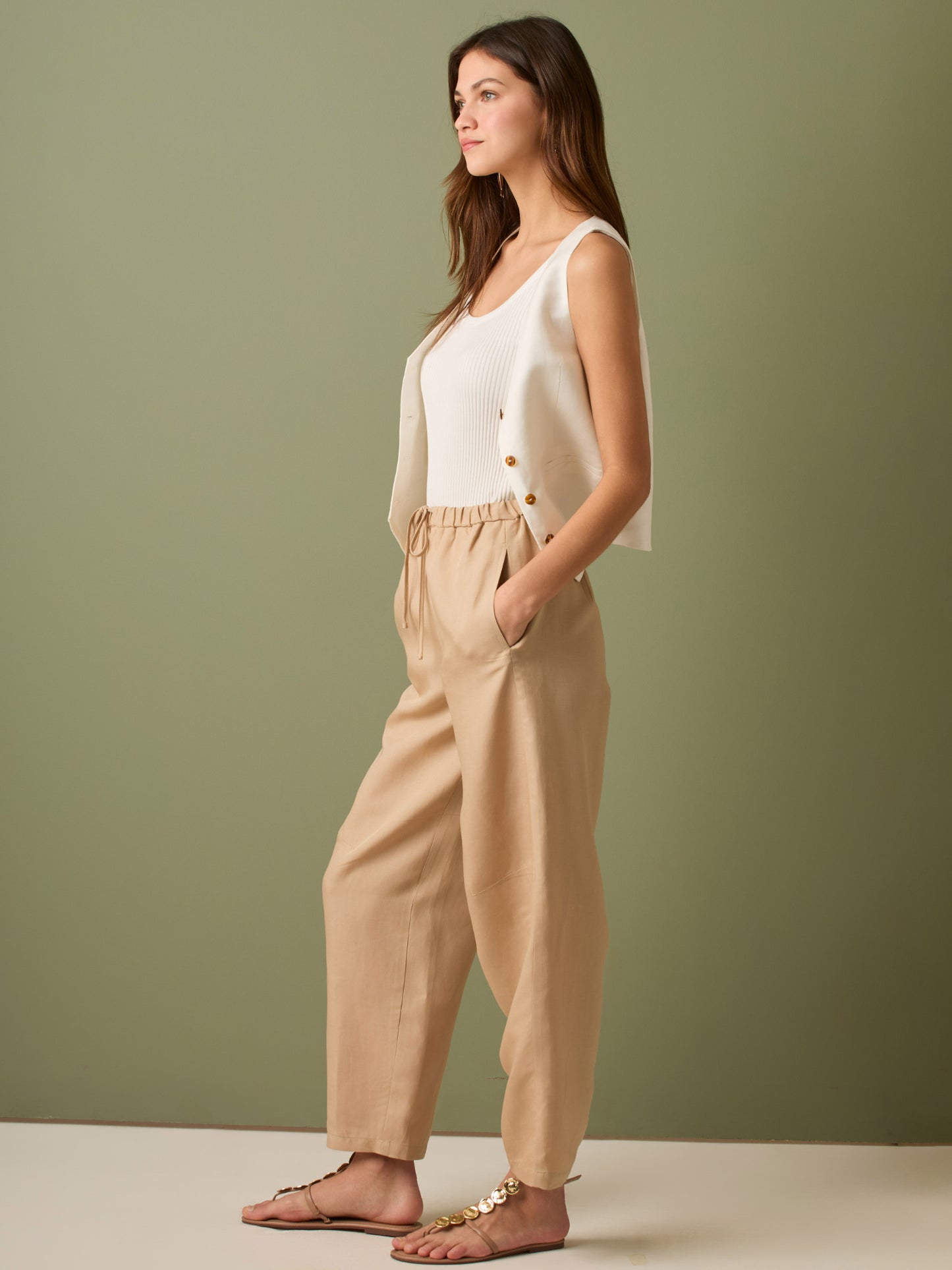 Pantalón de tiro medio con cintura elástica y cordón ajustable. Silueta relajada que cae con volumen en la cadera y se afina al tobillo, con bolsillos laterales y cortes decorativos en la pierna. Largo al tobillo con pequeña abertura en el bajo: la base moderna y versátil para elevar looks de día o de noche.

Detalles:

Color: Sand

Material: 77% Tencel 23% Lino 100% Rayón