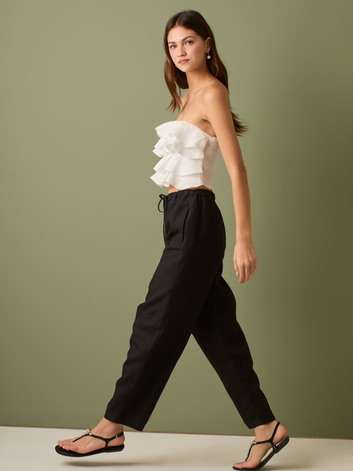 Pantalón de tiro medio con cintura elástica y cordón ajustable. Silueta relajada que cae con volumen en la cadera y se afina al tobillo, con bolsillos laterales y cortes decorativos en la pierna. Largo al tobillo con pequeña abertura en el bajo: la base moderna y versátil para elevar looks de día o de noche.

Detalles:

Color: Negro