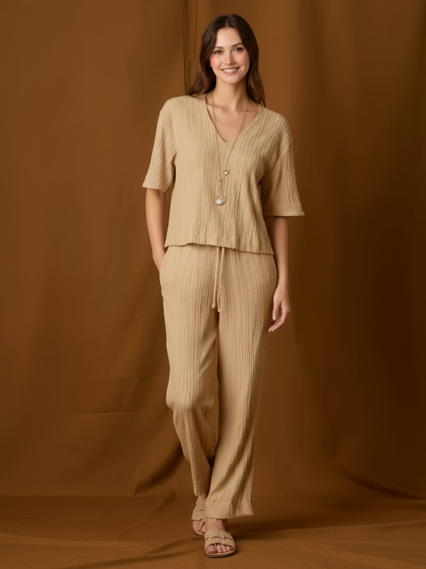 Pantalón fluido de silueta relajada y tiro medio, con pretina elástica y jareta ajustable. Pernera recta-amplia hasta el tobillo, bolsillos laterales y textura arrugada que aporta movimiento. Cómodo y versátil para el día a día o viajes; combínalo con tops mínima o la blusa a juego.
