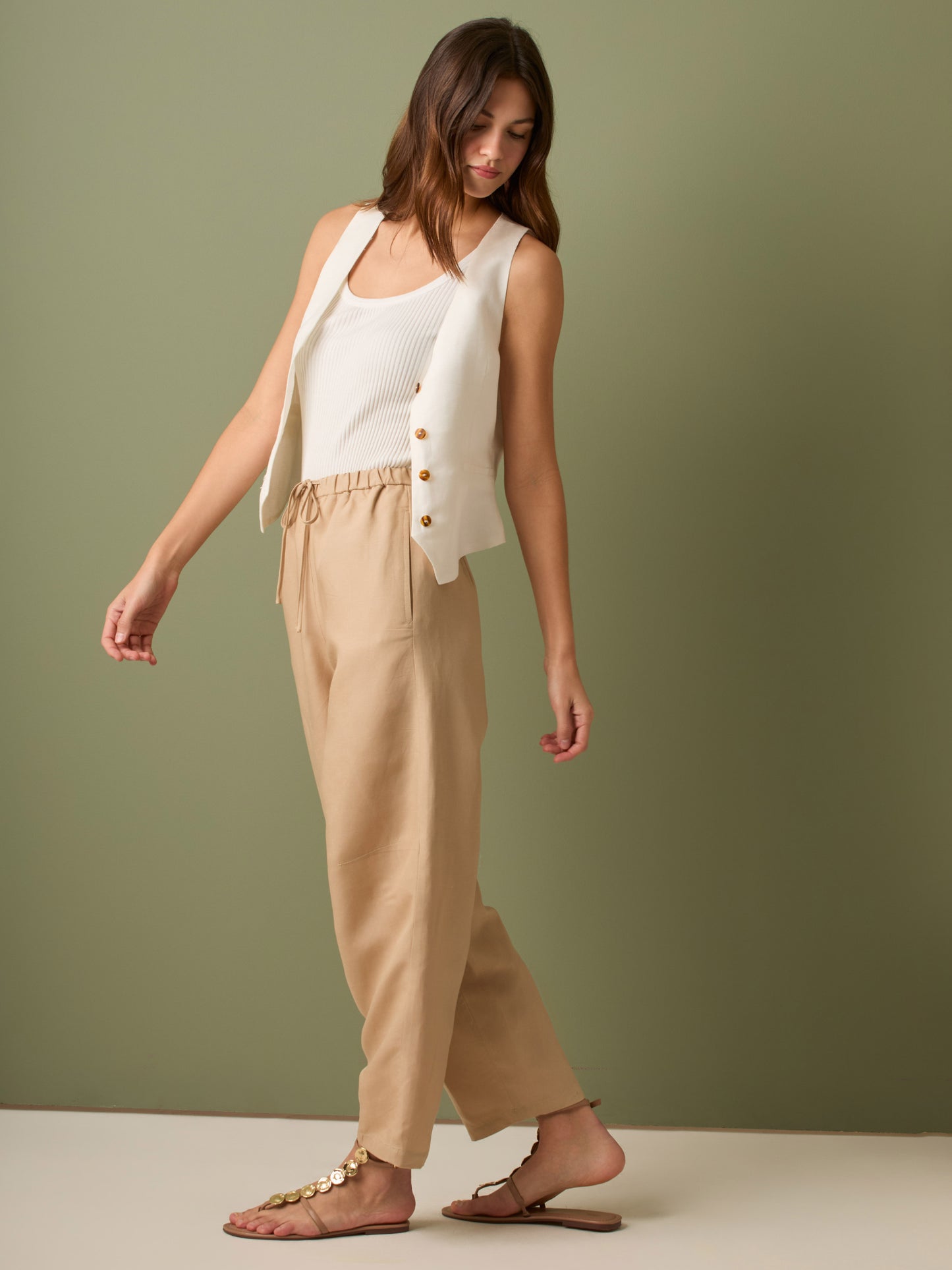 Pantalón de tiro medio con cintura elástica y cordón ajustable. Silueta relajada que cae con volumen en la cadera y se afina al tobillo, con bolsillos laterales y cortes decorativos en la pierna. Largo al tobillo con pequeña abertura en el bajo: la base moderna y versátil para elevar looks de día o de noche.

Detalles:

Color: Sand

Material: 77% Tencel 23% Lino 100% Rayón