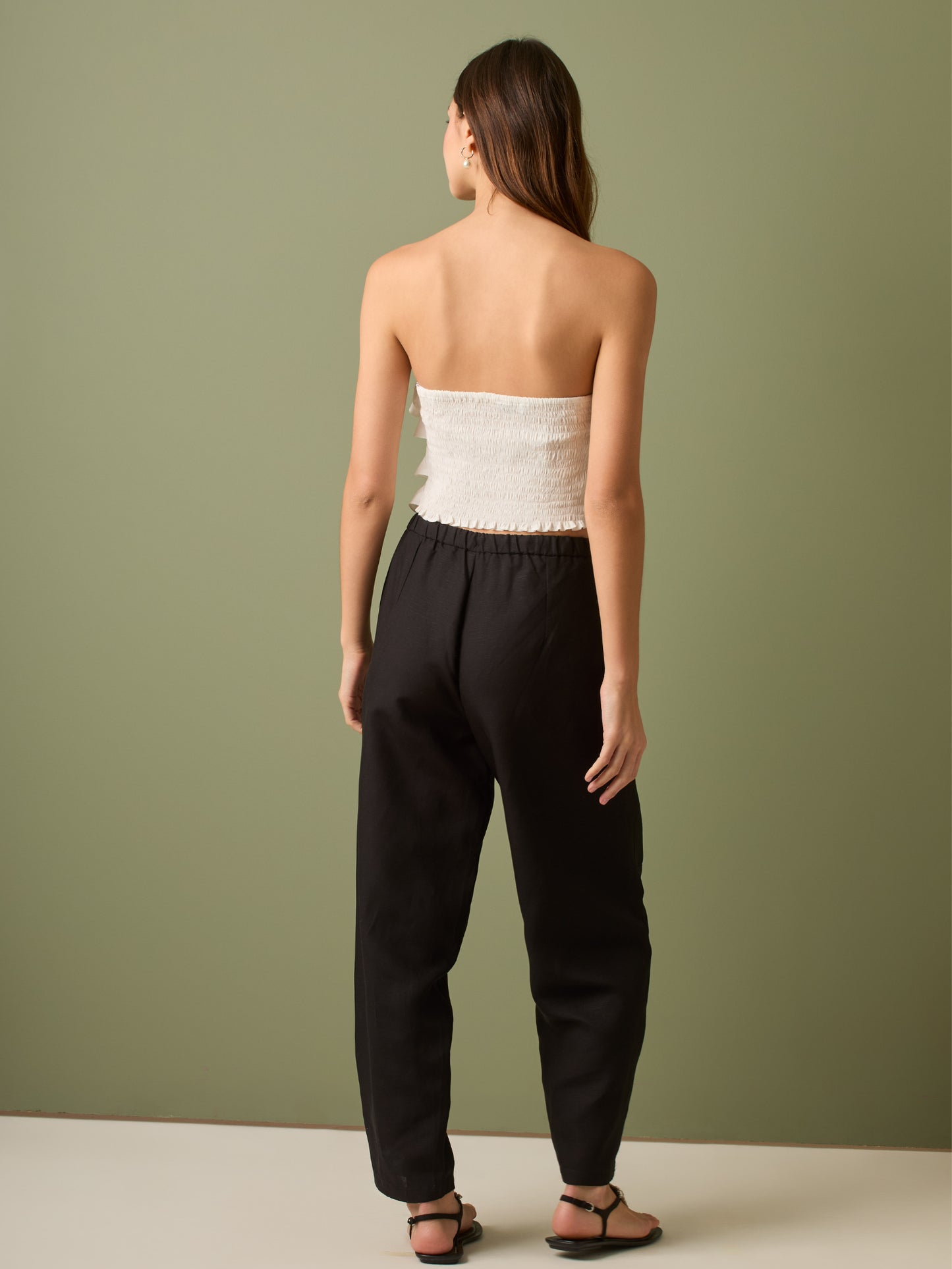 Pantalón de tiro medio con cintura elástica y cordón ajustable. Silueta relajada que cae con volumen en la cadera y se afina al tobillo, con bolsillos laterales y cortes decorativos en la pierna. Largo al tobillo con pequeña abertura en el bajo: la base moderna y versátil para elevar looks de día o de noche.

Detalles:

Color: Negro
