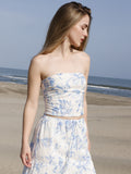 Esta blusa es tipo top strapless, ajustada al cuerpo, con escote recto y sin mangas, lo que deja los hombros y brazos completamente descubiertos. Está confeccionada en una tela ligera con estampado floral en tonos azul claro sobre fondo blanco, aportando un aire fresco y femenino. Su diseño corto deja ver ligeramente el abdomen, ideal para climas cálidos o looks playeros. Es una prenda versátil que combina estilo y comodidad.

Detalles:

Color: Blanco

Material: 100% Lyocel