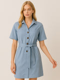Este vestido camisero de silueta recta combina la estructura de una prenda utilitaria con la frescura de un look contemporáneo. Con cuello tipo solapa, botones frontales contrastantes y bolsillos superiores de parche, incorpora un cinturón del mismo tejido que define la cintura y aporta feminidad. El largo sobre la rodilla lo convierte en una opción versátil para días cálidos, perfecta para el trabajo, una salida casual o un look urbano pulido.