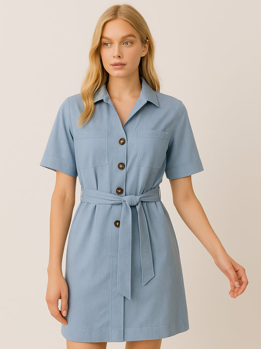 Este vestido camisero de silueta recta combina la estructura de una prenda utilitaria con la frescura de un look contemporáneo. Con cuello tipo solapa, botones frontales contrastantes y bolsillos superiores de parche, incorpora un cinturón del mismo tejido que define la cintura y aporta feminidad. El largo sobre la rodilla lo convierte en una opción versátil para días cálidos, perfecta para el trabajo, una salida casual o un look urbano pulido.