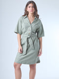 Este vestido camisero de silueta recta combina la estructura de una prenda utilitaria con la frescura de un look contemporáneo. Con cuello tipo solapa, botones frontales contrastantes y bolsillos superiores de parche, incorpora un cinturón del mismo tejido que define la cintura y aporta feminidad. El largo sobre la rodilla lo convierte en una opción versátil para días cálidos, perfecta para el trabajo, una salida casual o un look urbano pulido.