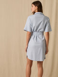 Este vestido camisero de silueta recta combina la estructura de una prenda utilitaria con la frescura de un look contemporáneo. Con cuello tipo solapa, botones frontales contrastantes y bolsillos superiores de parche, incorpora un cinturón del mismo tejido que define la cintura y aporta feminidad. El largo sobre la rodilla lo convierte en una opción versátil para días cálidos, perfecta para el trabajo, una salida casual o un look urbano pulido.