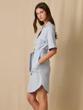 Este vestido camisero de silueta recta combina la estructura de una prenda utilitaria con la frescura de un look contemporáneo. Con cuello tipo solapa, botones frontales contrastantes y bolsillos superiores de parche, incorpora un cinturón del mismo tejido que define la cintura y aporta feminidad. El largo sobre la rodilla lo convierte en una opción versátil para días cálidos, perfecta para el trabajo, una salida casual o un look urbano pulido.