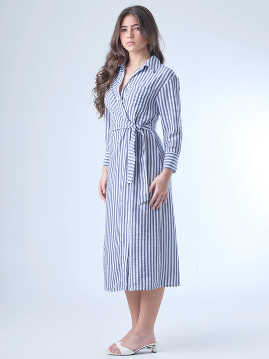 Vestido camisero midi con diseño de rayas verticales. Tiene cuello clásico, mangas largas con puños y un corte cruzado al frente que se ajusta con un lazo a la cintura. La falda cae con movimiento sutil y el ajuste en la cintura define la silueta de forma favorecedora. Es una prenda cómoda, estructurada y con un aire sofisticado.

Detalles:

Color: Azul