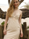 Vestido largo de tirantes delgados con escote halter. Tiene un detalle fruncido en el busto con abertura frontal y un pequeño corte debajo del pecho. La falda incluye una abertura frontal que aporta movimiento y frescura al diseño. Silueta ajustada al cuerpo con caída fluida. Ideal para un look de playa o verano.